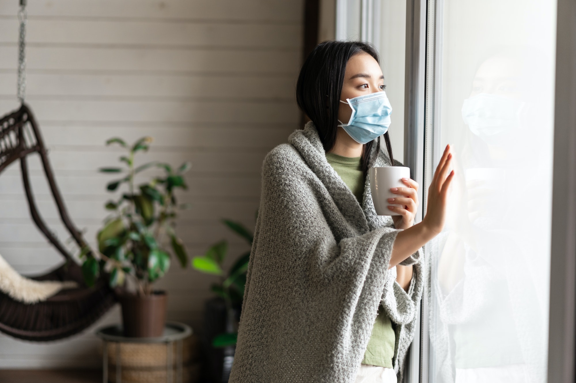 Asian girl in medical face mask, yearning go outside, being sick with covid 19 and staying on self